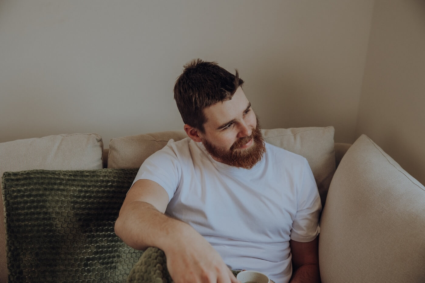 Mann sitzt entspannt auf dem Sofa mit einer Tasse Tee – Darstellung von innerer Ruhe, mentaler Balance und Stärkung des Nervensystems mit Ayurveda.