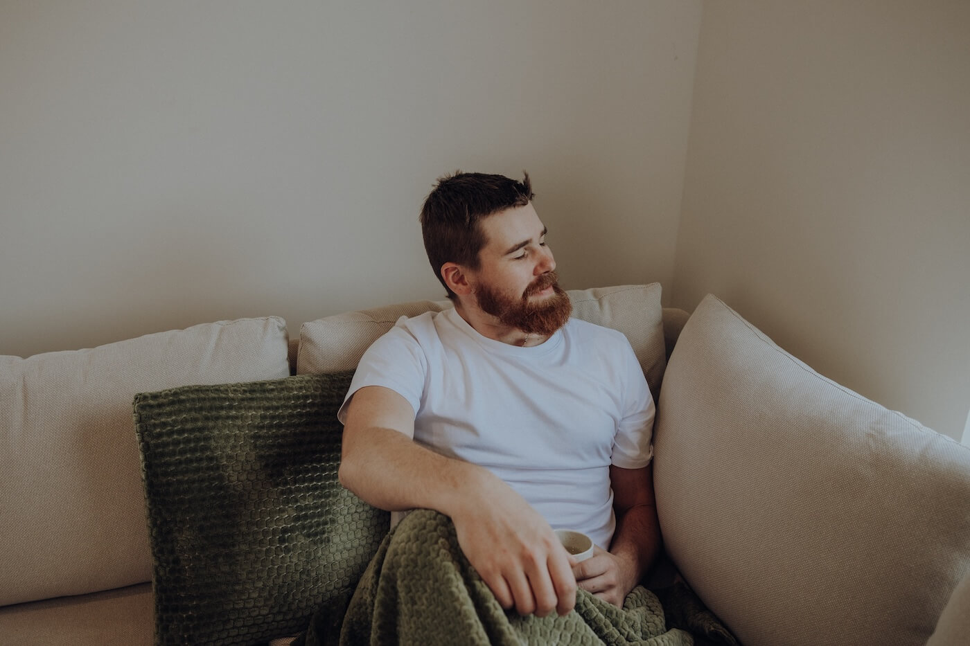 Mann entspannt auf dem Sofa mit einer Tasse – Darstellung von Ruhe, Balance und gezielter Unterstützung individueller Bedürfnisse durch Ayurveda.