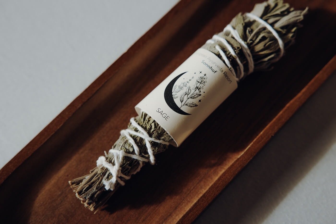 Bündel aus Salbei Räucherwerk auf Holzschale – Darstellung eines natürlichen Rituals zur energetischen Reinigung.