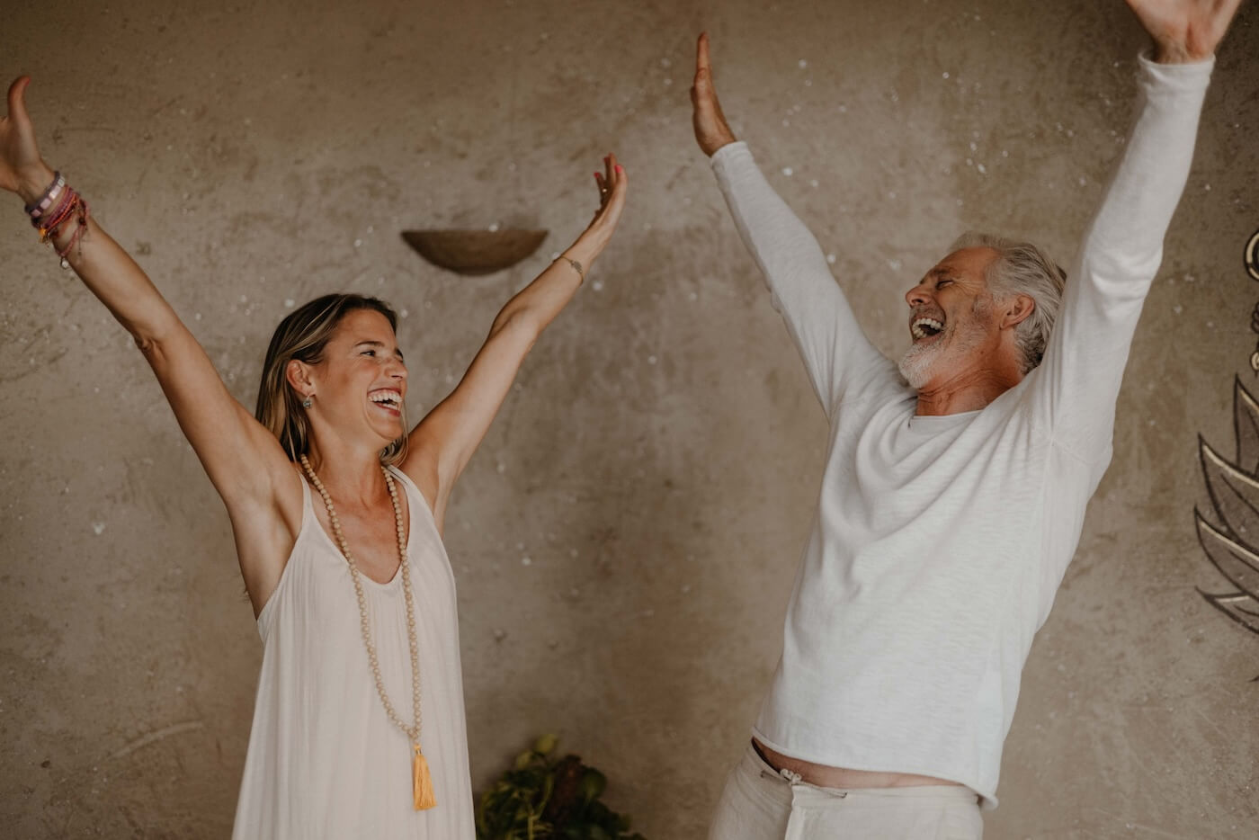 Zwei Menschen strecken freudig die Arme nach oben – Symbol für positive Energie, Lebensfreude und innere Balance durch Ayurveda.