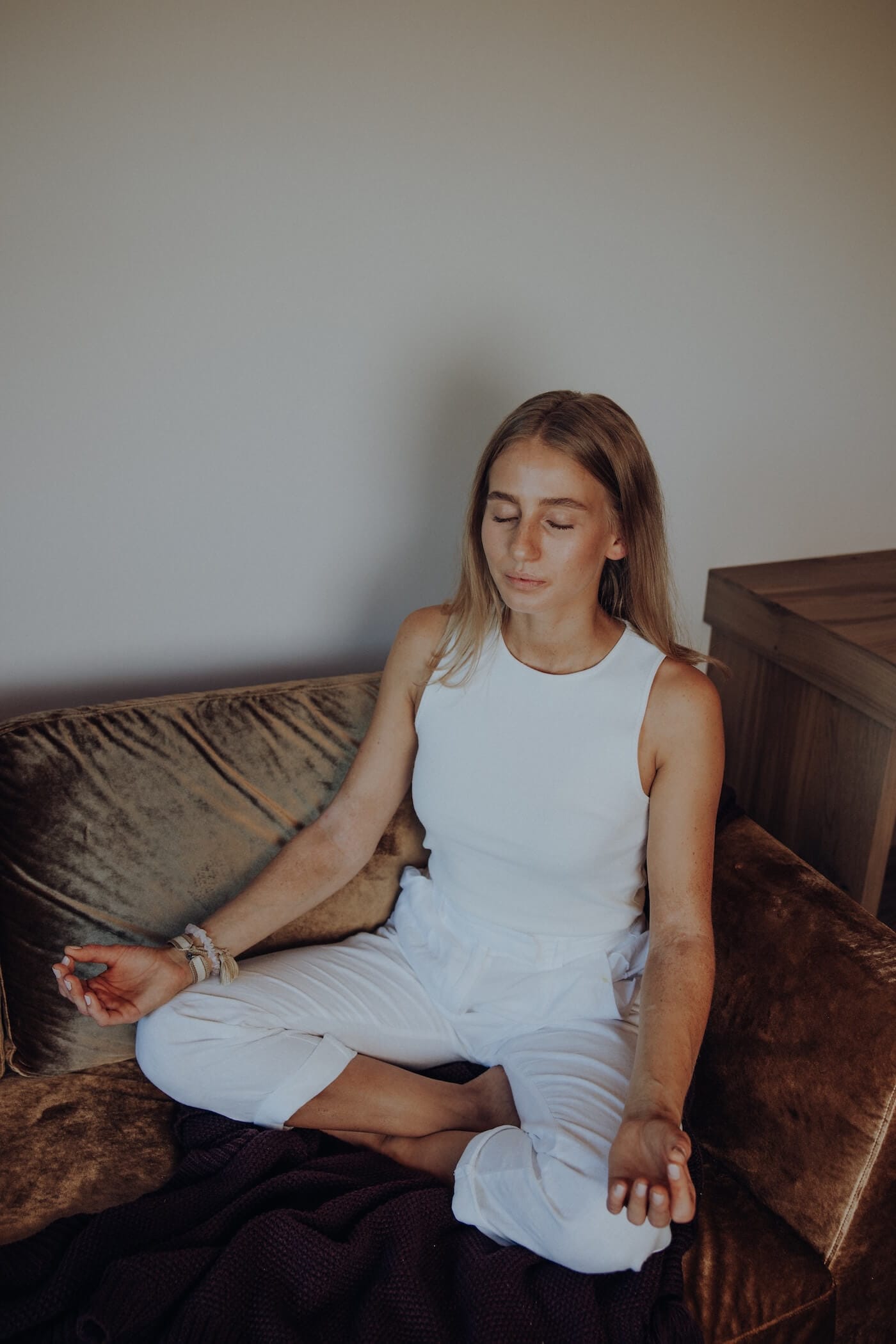 Frau meditiert entspannt auf einem Sofa – Ayurveda Ritual zur Beruhigung des Vata Doshas und für innere Balance.