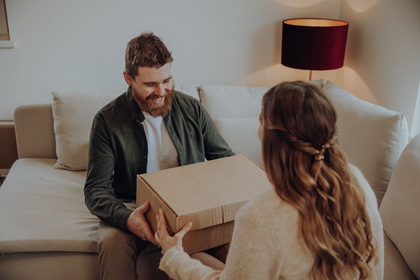 Paar öffnet gemeinsam ein Paket mit Produkten – steht für Freude, Wohlbefinden und regelmäßige Selfcare-Rituale zuhause.
