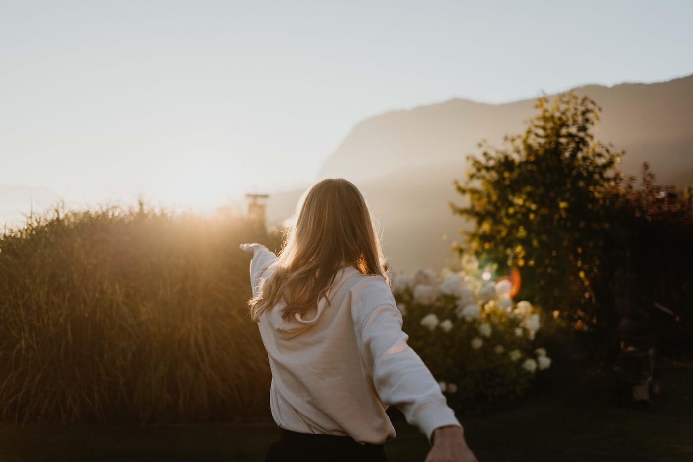 Frau breitet die Arme in der Natur aus – Ausdruck von Freiheit, Leichtigkeit und innerer Reinigung durch Ayurveda Detox Rituale.