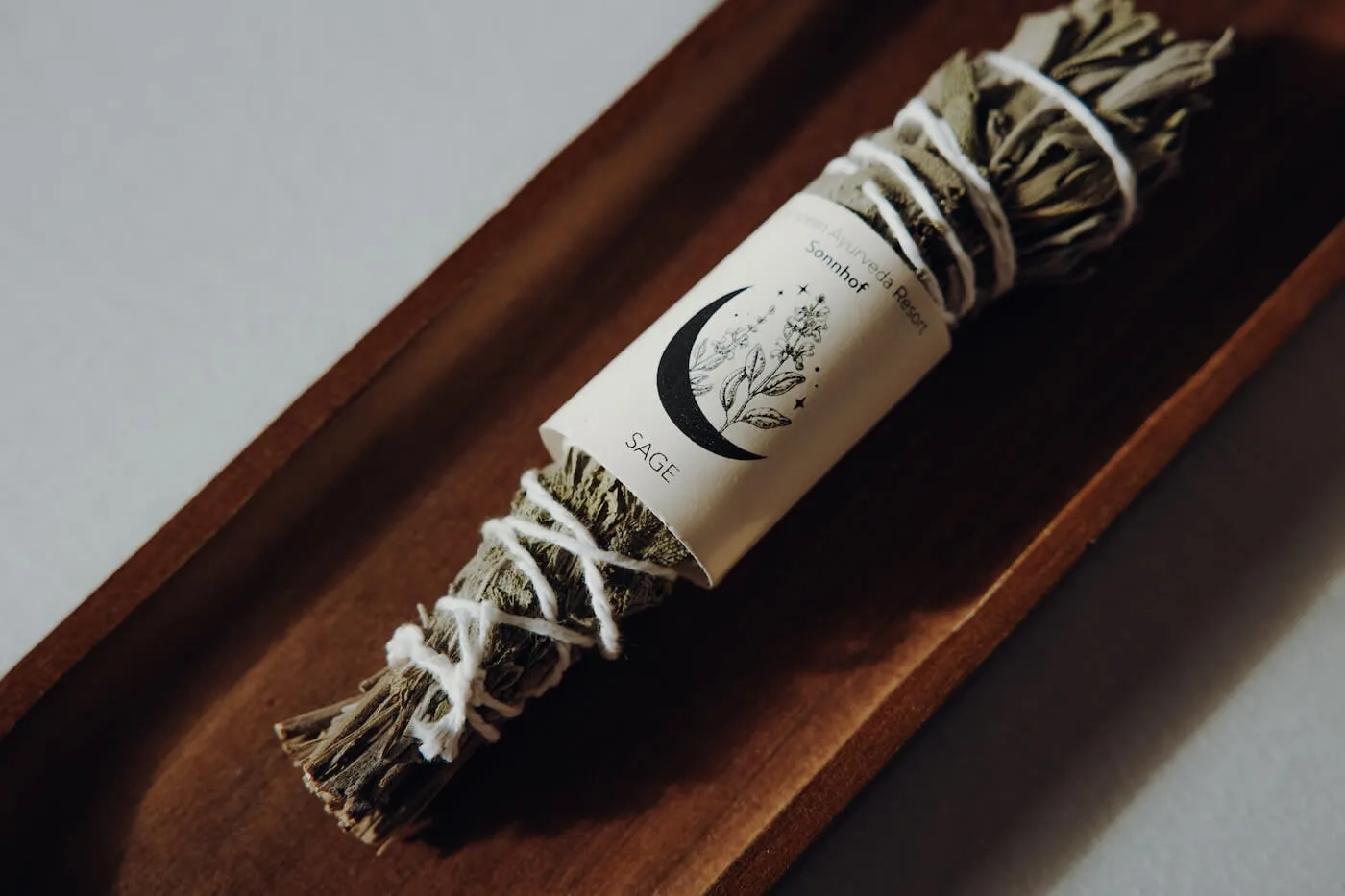 Bündel aus Salbei Räucherwerk auf Holzschale – Darstellung eines natürlichen Rituals zur energetischen Reinigung.