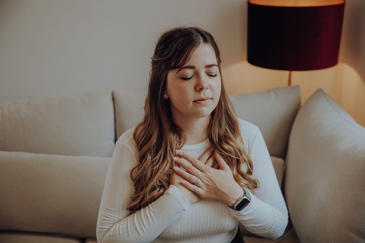 Frau meditiert entspannt auf einem Sofa – Ayurveda Ritual zur Beruhigung von Pitta und Förderung innerer Balance.