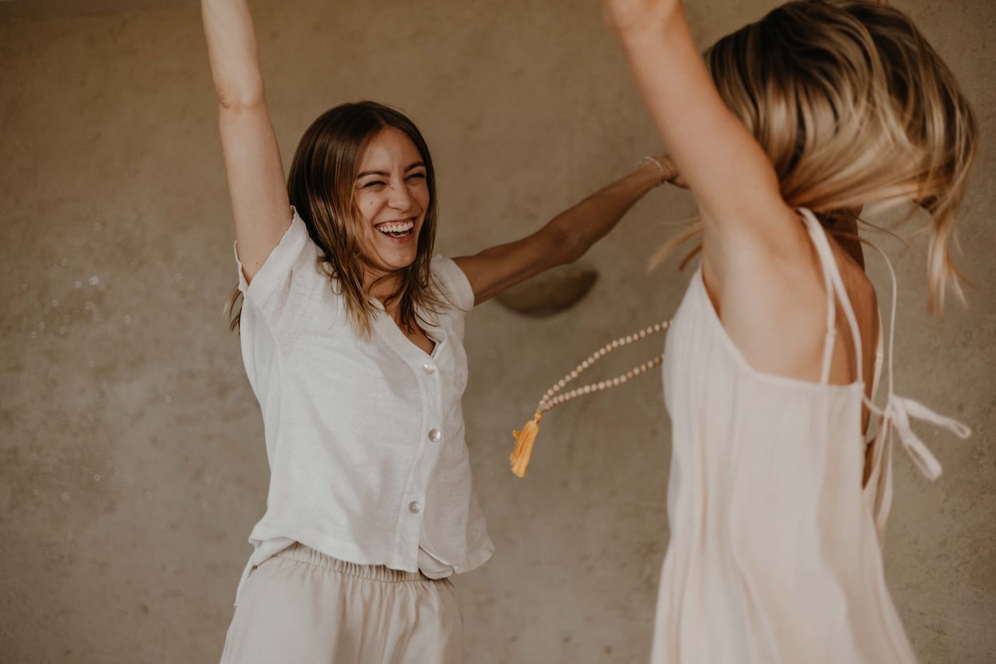 Zwei Frauen tanzen und lachen – Ausdruck von Lebensenergie, Vitalität und gesteigerter Leistungsfähigkeit durch Ayurveda.